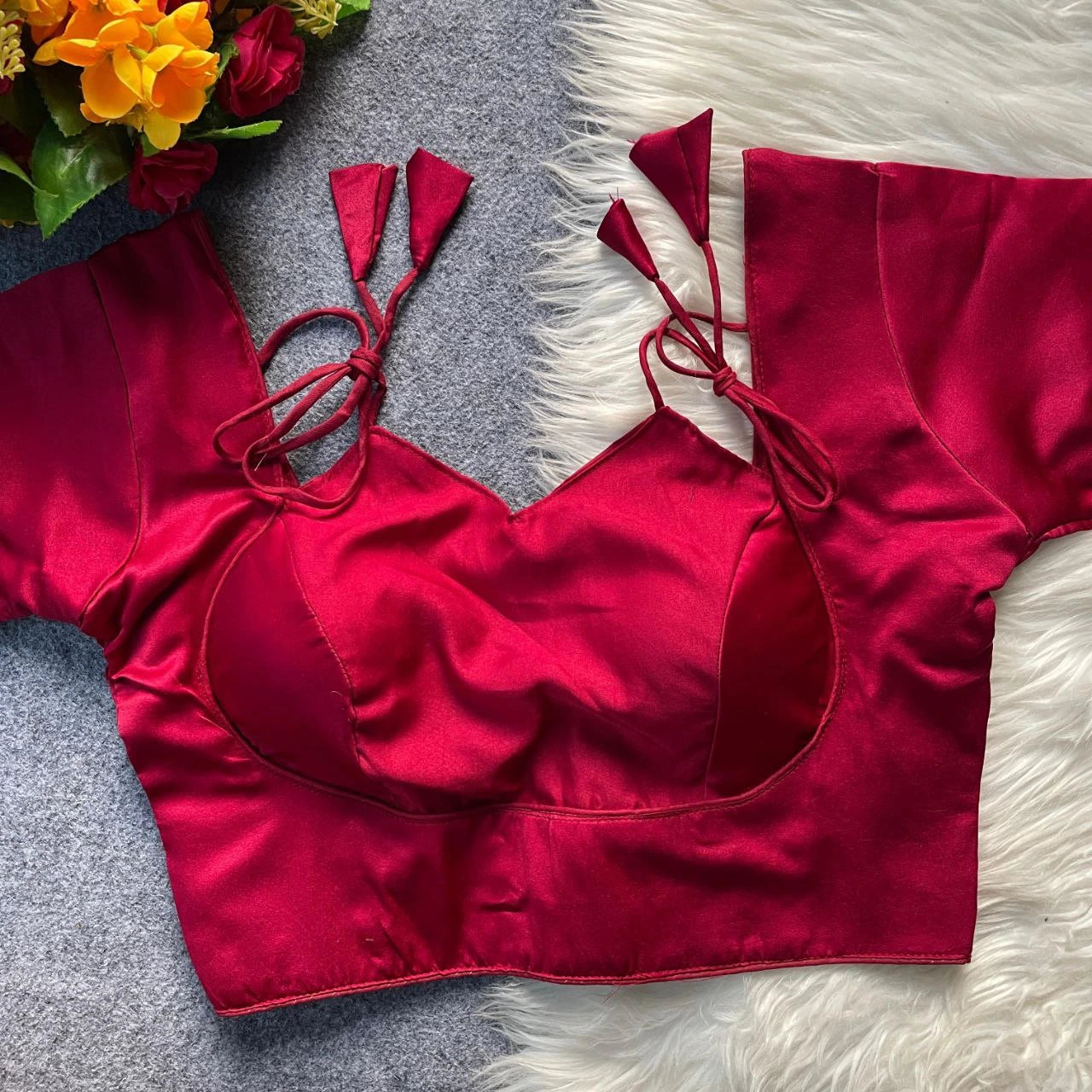 Red bikini top on a textured surface with flowers in the corner